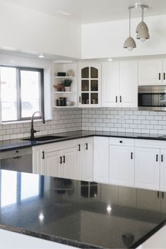 a kitchen with white cabinets and black counter tops