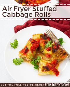 an air fryer stuffed cabbage rolls on a white plate with a fork and garnish