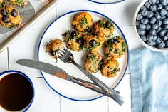 blueberry muffins on a plate with a fork and bowl of blueberries