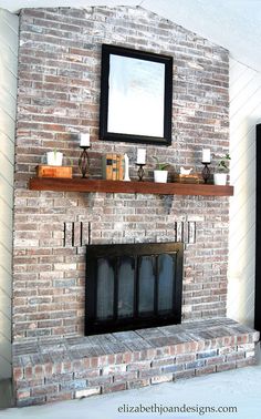 a brick fireplace with candles on the mantle and a mirror above it in a living room