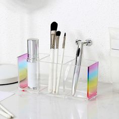 an assortment of makeup brushes in a clear holder on a counter top with other items