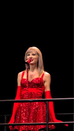 a woman in a red dress singing into a microphone