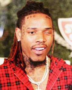 a close up of a person wearing a red shirt with dreadlocks on his head