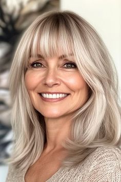 Save this pin for the best medium-length hairstyles for women over 50 with bangs. This long bob, or “lob,” with bangs has soft, face-framing layers to ensure the style feels light and easy. The key to this cut is the way the layers frame the face. Blonde Lob With Bangs, Medium Length With Bangs, French Bangs