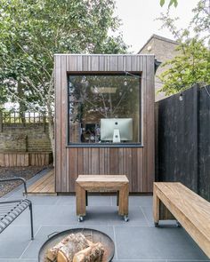 a small wooden building with a grill and bench in the foreground next to it