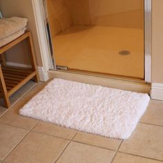 a bath room with a toilet and a rug on the floor in front of a glass door