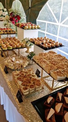 an assortment of desserts are displayed on a buffet table