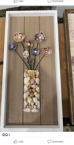 a vase filled with shells and flowers on top of a wooden table