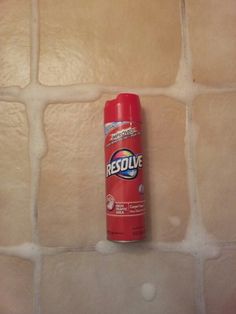 a bottle of red deodorant sitting on top of a tiled countertop