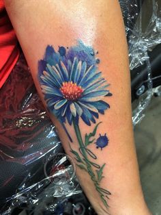 a woman's leg with a blue flower tattoo on it