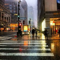 people are crossing the street in the rain