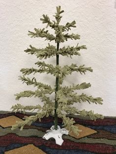 a small white christmas tree sitting on top of a table next to a rug and wall