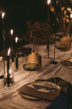 the table is set with candles, plates and napkins for an elegant dinner party