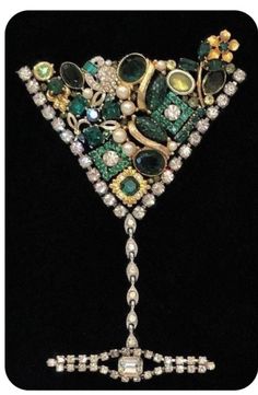 a green and white brooch with jewels on it