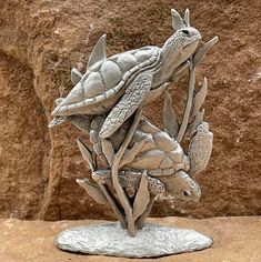 a statue of a turtle on top of a plant in front of a rock wall