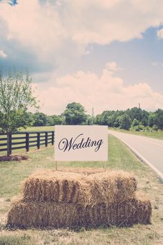 a wedding sign sitting on top of hay bales in the middle of a road