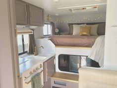 the interior of a camper with sink, stove and bed in it's corner