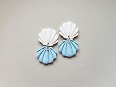 "Add a touch of seaside charm to your look with these handmade seashell dangle earrings. Featuring glitter white and baby blue double shells, these earrings are perfect for lovers of all things coastal. The stainless steel posts ensure durability and comfort for everyday wear. Embrace your love for the ocean with these unique and whimsical earrings that will surely make a statement wherever you go. Size: 43 x 22 mm (1.69\" x 0.86\"). You might also enjoy these similar polymer clay nature inspire White Shell Jewelry With Ocean-inspired Style, White Shell-shaped Ocean-inspired Jewelry, Ocean-inspired White Shell-shaped Jewelry, White Ocean-inspired Jewelry For Summer, Ocean-inspired White Jewelry For Summer, Ocean-inspired White Summer Jewelry, Handmade Ocean Color Jewelry For Summer, Handmade Ocean Color Summer Jewelry, White Shell-shaped Beachy Jewelry