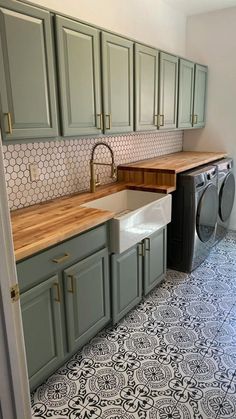 a washer and dryer in a small room with green cabinets, patterned flooring