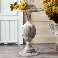 two white vases with flowers on top of them sitting in front of a door