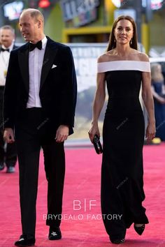 a man and woman in formal wear walk down the red carpet