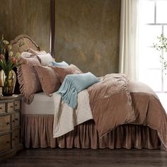 a bed sitting in a bedroom next to a dresser with flowers on top of it