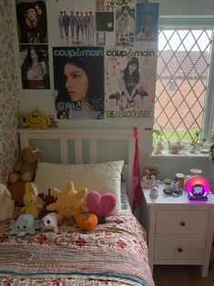 a bedroom with posters on the wall and stuffed animals on the bed in front of it