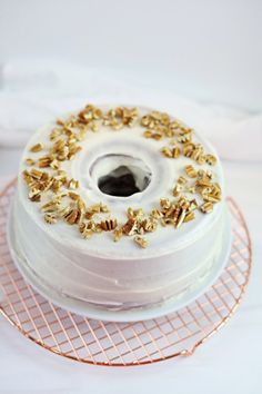 a cake with white frosting and gold sprinkles sitting on a wire rack