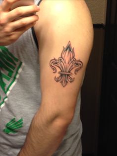 a man with a fleur de lis tattoo on his arm holding a cell phone