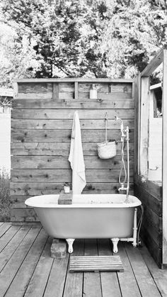 an old fashioned bathtub sitting on top of a wooden deck next to a shower