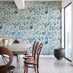 a dining room with blue wallpaper and wooden chairs