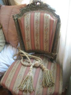 an old chair with tassels and rope tied to it's back sitting on a bed