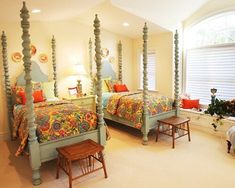 a bedroom with four poster beds and colorful comforter on the bed, along with two small stools