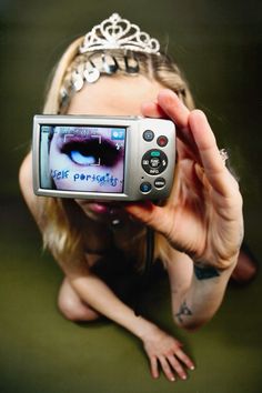 a woman holding up a cell phone to take a selfie with her eyes closed