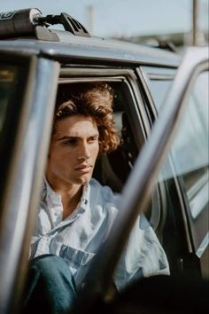 a man sitting in the driver's seat of a car with his head out the window