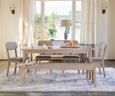 a dining room table with chairs and a bench in front of a large open window