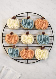 cupcakes are arranged on a wire rack with frosting in the shape of pumpkins