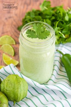 a green smoothie in a mason jar surrounded by limes and cilantro