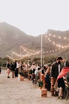 a group of people standing next to each other near chairs and lights in the sand