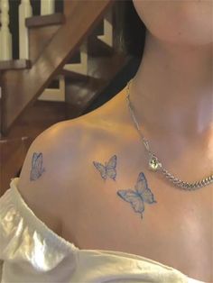 a woman with tattoos on her chest and butterfly tattoo on her shoulder, standing in front of stairs