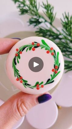 a hand holding a button with a wreath on it