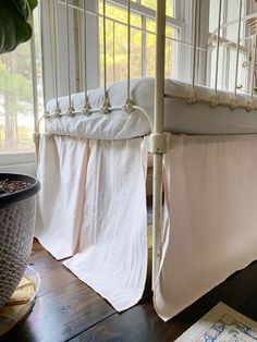 a white crib in a room next to a potted plant