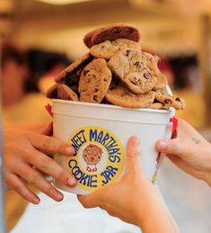 two people holding up a bucket of cookies and ice cream