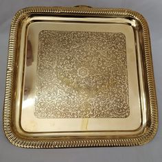 an ornately decorated gold tray with beaded edges on a white tablecloth background