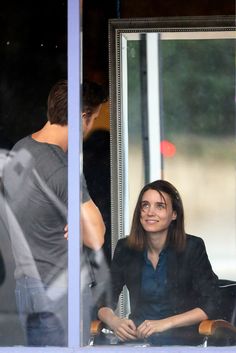 a woman sitting in front of a window next to a man