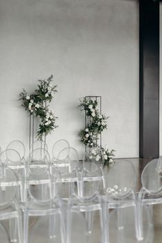 rows of clear chairs with flowers on them in front of a white wall and floor