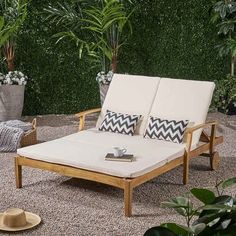 an outdoor chaise lounge chair in front of a green wall and potted plants