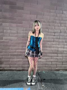 a woman standing in front of a brick wall wearing fishnet stockings and tights