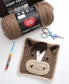 a crocheted cow is next to some scissors and yarn