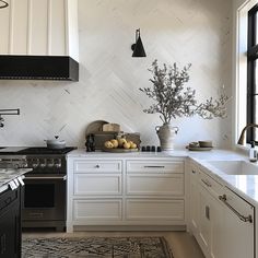 a kitchen with white cabinets, black appliances and a potted plant on the counter